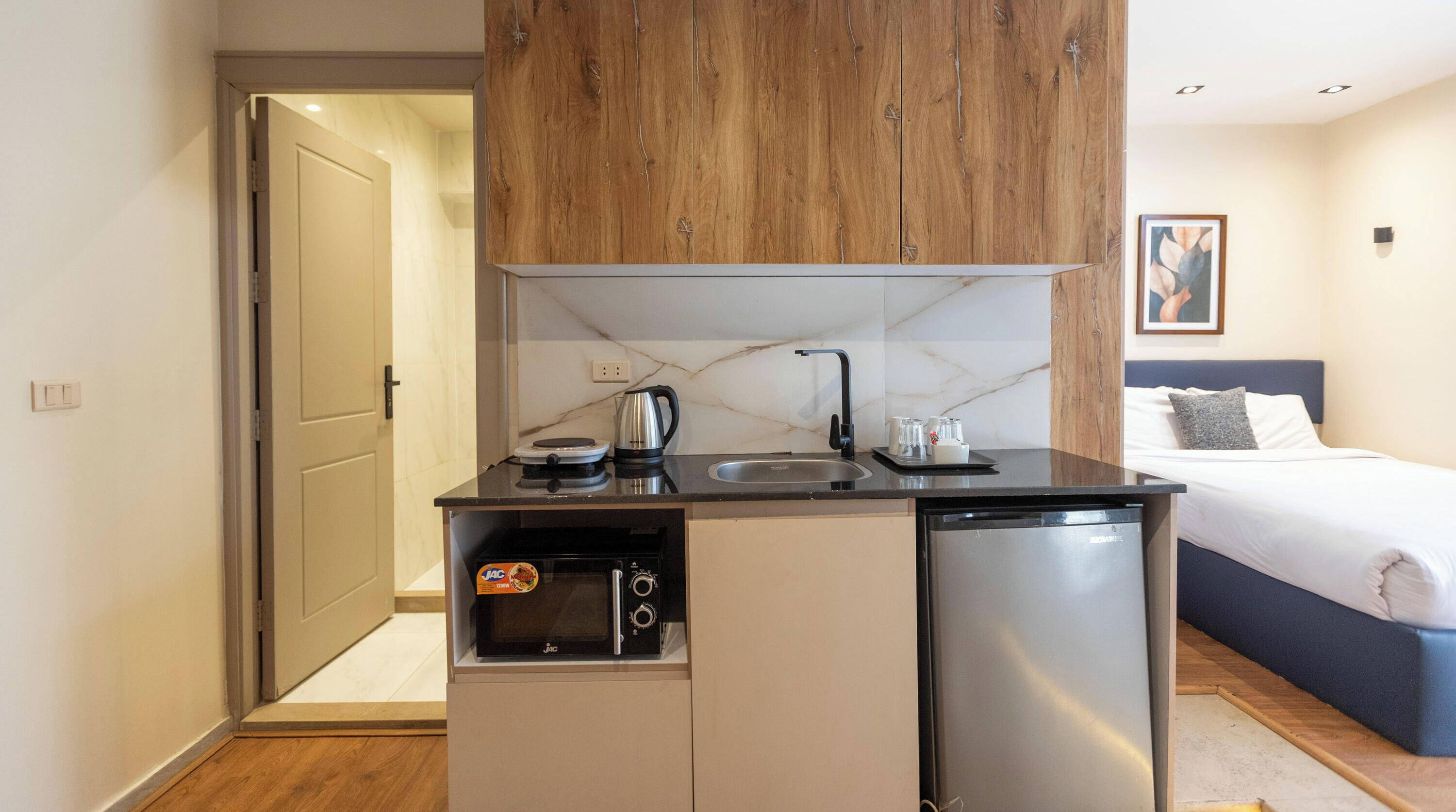 Una kitchenette compacta con lavavajillas integrado, cafetera y horno pequeño.