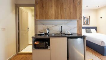 Una kitchenette compacta con lavavajillas integrado, cafetera y horno pequeño.