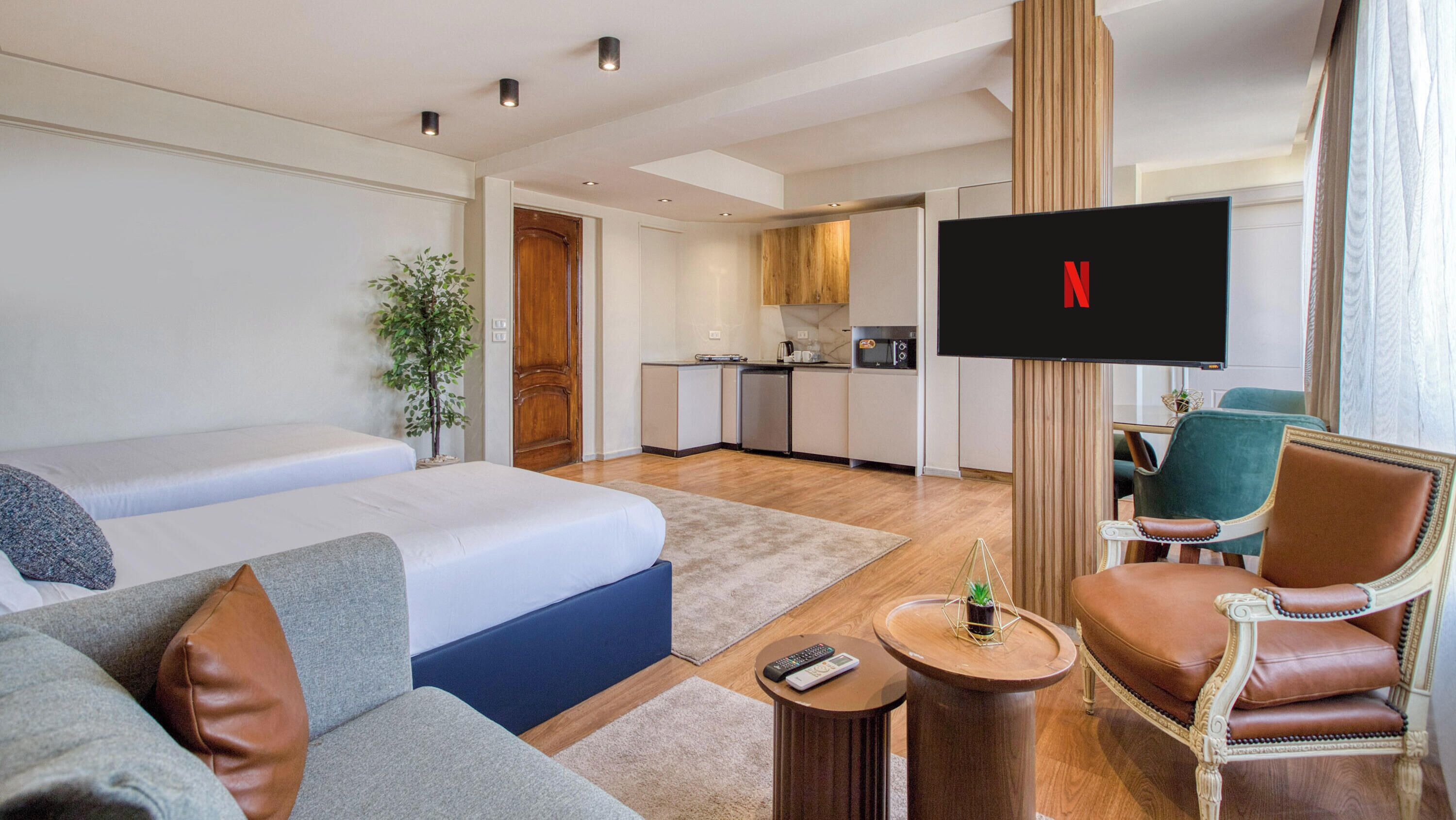 Une chambre d’hôtel équipée d’un lit, d’un canapé, d’un fauteuil, d’une télévision et d’une kitchenette.