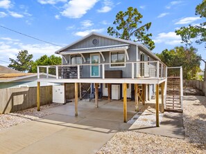 Une maison à deux étages avec un balcon, une terrasse couverte et une terrasse en bois.