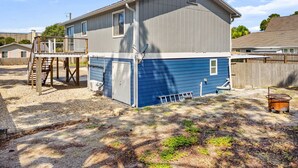 Ein zweistöckiges Haus mit Terrasse, Satellitenschüssel und Feuerstelle im Garten.