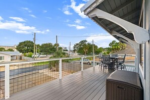 A balcony with a view of a street, a fence, and a table with chairs. - Beach House Hideaway Near Schooners, Sand & Grand Lagoon Fun (Panama City)