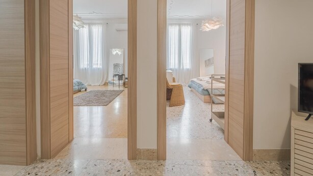 Um interior moderno com um corredor que dá para um quarto, uma sala de jantar e uma sala de estar.