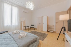 A hotel room with a bed, a desk, a chair, a wardrobe, and a television. - Aloha Lodge Apartment Trapani (Trapani)