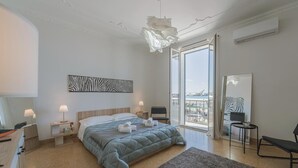 Quarto moderno com uma cama grande, varanda com vista e uma obra de arte com tema de zebra na parede.