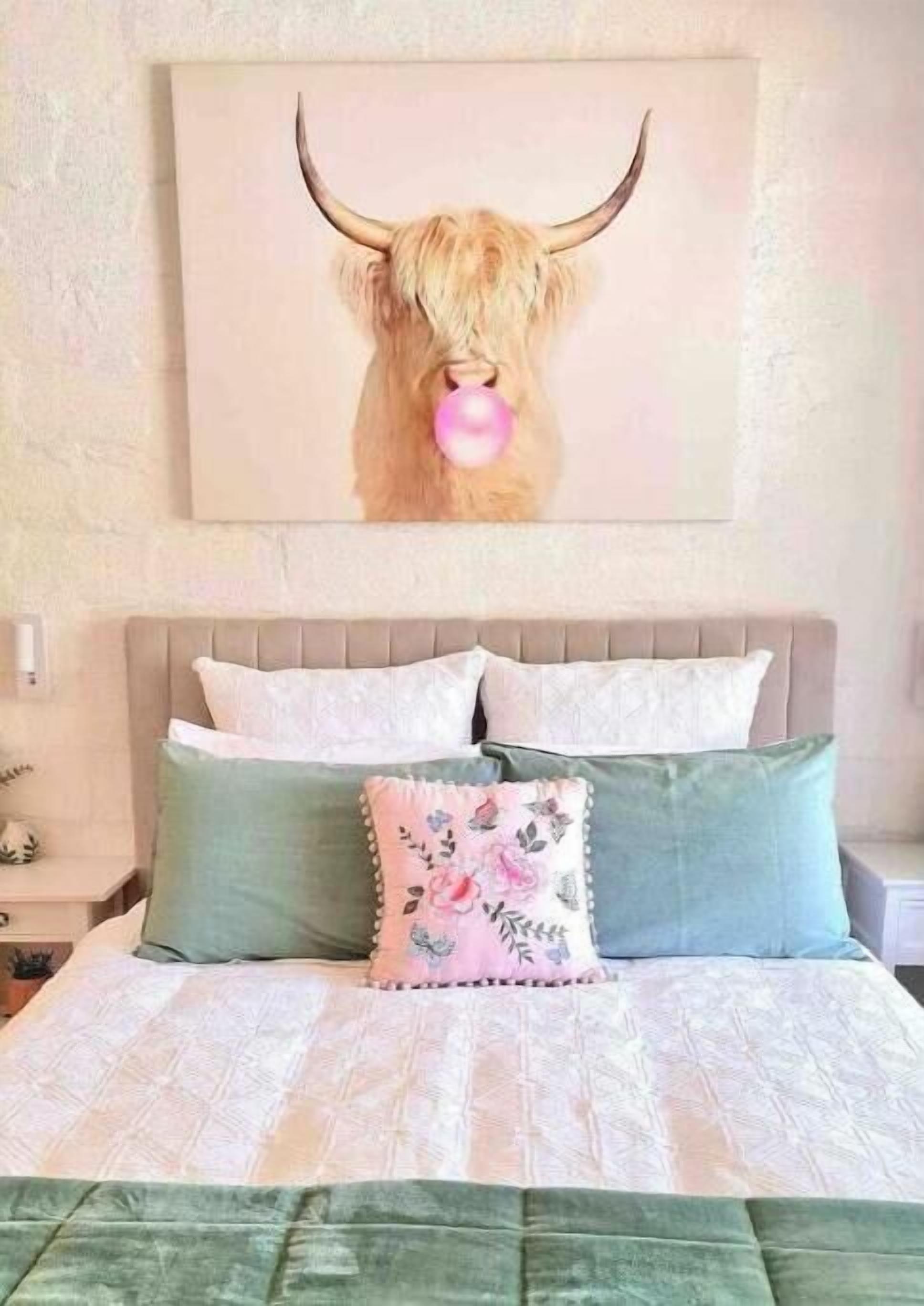 Ein Bett mit Kopfteil, Kissen und einem Wandbild eines Stiers.