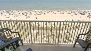 Ein Balkon mit Blick auf einen Strand, an dem sich Menschen und Sonnenschirme befinden.