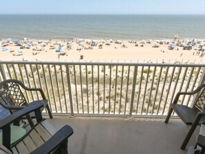 Ein Balkon mit Blick auf einen Strand, an dem sich Menschen und Sonnenschirme befinden.