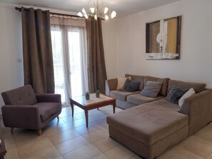 A living room with a sofa, armchair, and a coffee table. - Spacious apartamens nearthe mall (Pafos)