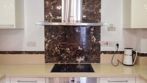 A kitchen with a built-in oven, a stainless steel range hood, and a marble backsplash. - Spacious apartamens nearthe mall (Pafos)