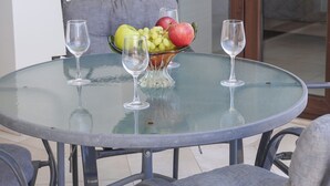A round glass table with two wine glasses and a bowl of fruit. - Spacious apartamens nearthe mall (Pafos)