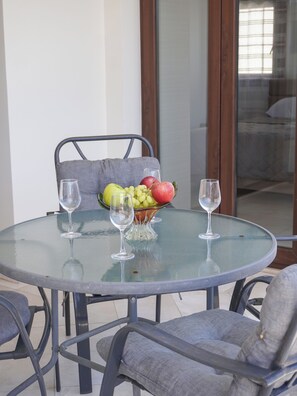 A round glass table with two wine glasses and a bowl of fruit. - Spacious apartamens nearthe mall (Pafos)