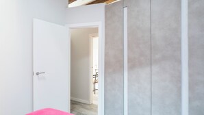 Ein Zimmer mit einem rosa Bett, einer weißen Tür und einem grauen Kleiderschrank.