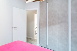 A room with a pink bed, a white door, and a grey wardrobe. - Apartment with a terrace in the Gothic Quarter (Barcelona)