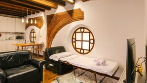 Ein Raum mit Massagetisch, einer Ledersofa, einem Fernseher und einer Küchenzeile.