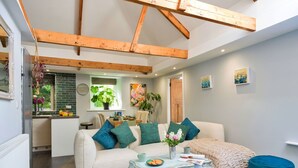A cozy living room with a sofa, coffee table, and a blue ottoman. - Wonderful  villa for 6 people with WIFI (Porthleven)
