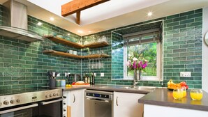 A modern kitchen with green tiles, stainless steel appliances, and a window with a view. - Wonderful  villa for 6 people with WIFI (Porthleven)