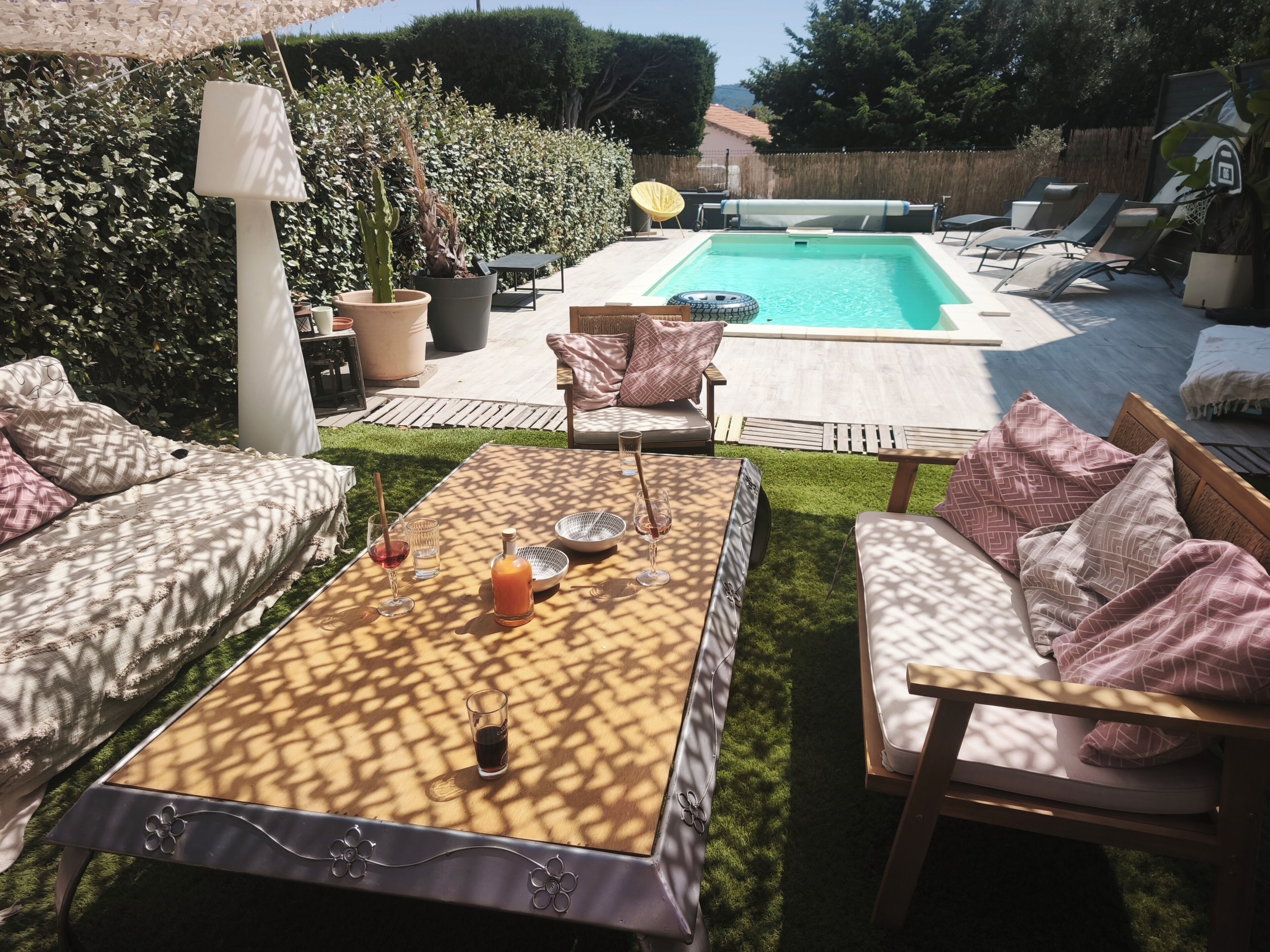 Un espace aménagé au bord de la piscine, avec un transat, une table avec des boissons et un coin salon confortable.