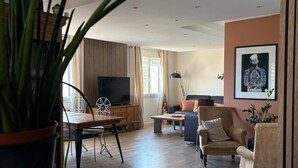 Uma sala de estar moderna com piso de madeira, televisão, sofá e mesa de centro.
