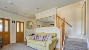 A living room with a sofa, a staircase, and a mirror. - Beautiful  villa for 5 people with WIFI, TV and patio (Inverness)