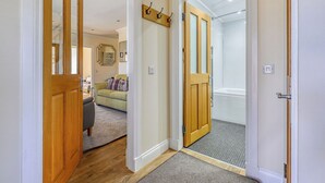 A hallway with wooden doors, a mirror, a coat rack, and a grey carpet. - Beautiful  villa for 5 people with WIFI, TV and patio (Inverness)
