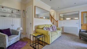 A living room with a sofa, a small table, a purple rug, and a staircase. - Beautiful  villa for 5 people with WIFI, TV and patio (Inverness)