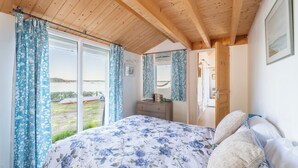 Quarto com cama, penteadeira, espelho e janela com cortinas.