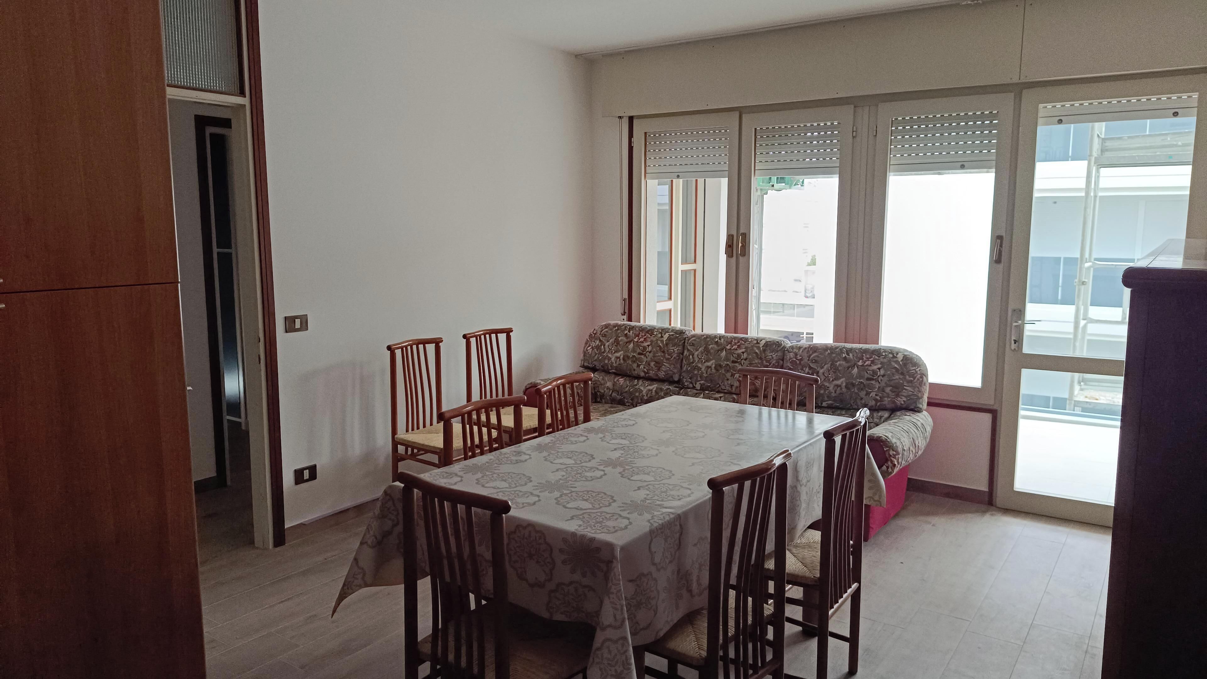 A dining area with a table, chairs, and a sofa.
