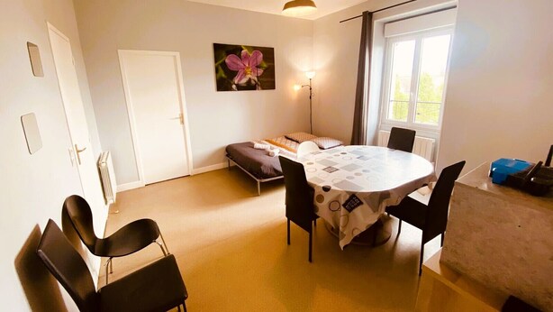 Quarto com uma mesa redonda, cadeiras, um sofá, um radiador, uma porta e uma janela.