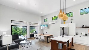A modern kitchen with a central island, dining area with chairs, and a large window overlooking greenery. - New Listing • Villa Emsita Hermosa • 3 BR Villa • Private Pool (Playa Hermosa)