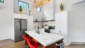 A modern kitchen with a central island, stainless steel appliances, and red bar stools. - New Listing • Villa Emsita Hermosa • 3 BR Villa • Private Pool (Playa Hermosa)
