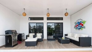 A modern outdoor seating area with a grill, wicker furniture, and a wall mural. - New Listing • Villa Emsita Hermosa • 3 BR Villa • Private Pool (Playa Hermosa)