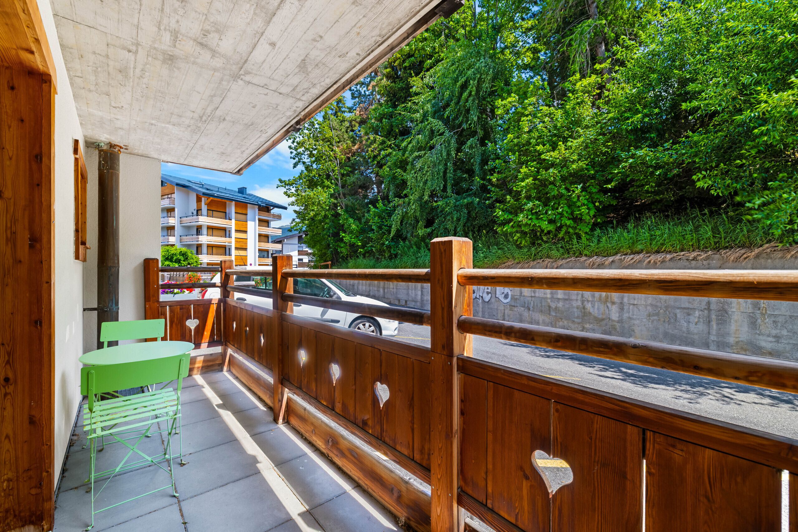 Ein Balkon mit Holzgeländer, einem grünen Stuhl und einem Tisch.