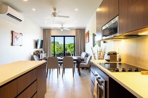 A modern kitchen with a dining area, large windows, and a view of greenery. - Chic 2BR | Beach, Town & Elevated Views (Huatulco)