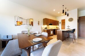 A modern kitchen with wooden cabinets, a built-in oven, and a dining area with a wooden table and chairs. - Chic 2BR | Beach, Town & Elevated Views (Huatulco)