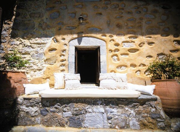 A stone wall with a doorway, a bench with cushions, and potted plants. - Villa Askyfou, Traditional Villas Askyfou (Crete)