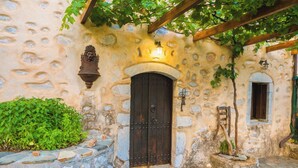 A stone building with a dark wooden door, a welcome mat, and a small window. - Villa Askyfou, Traditional Villas Askyfou (Crete)