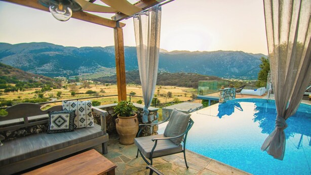 A poolside area with a view of mountains, a wooden pergola, a seating area with cushions, and a stone table. - Villa Askyfou, Traditional Villas Askyfou (Crete)