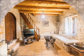 Ein rustikales Steinambiente mit einer Holztreppe, einem Fernseher, einer Badewanne und einem Essbereich.