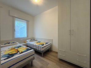 A bedroom with two beds, a wardrobe, a window, and a door. - Beachfront, Modern Flat With Lovely Garden (San Michele al Tagliamento)