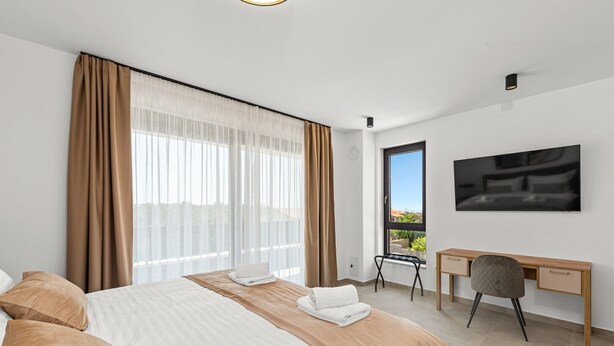 Een hotelkamer met een bed, een bureau, een stoel, een televisie en uitzicht op het omliggende landschap.