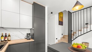 Een moderne keuken met een marmeren aanrecht, een koffieapparaat en wijnflessen.