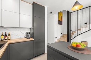 Eine moderne Küche mit Marmorarbeitsplatte, einer Kaffeemaschine und Weinflaschen.