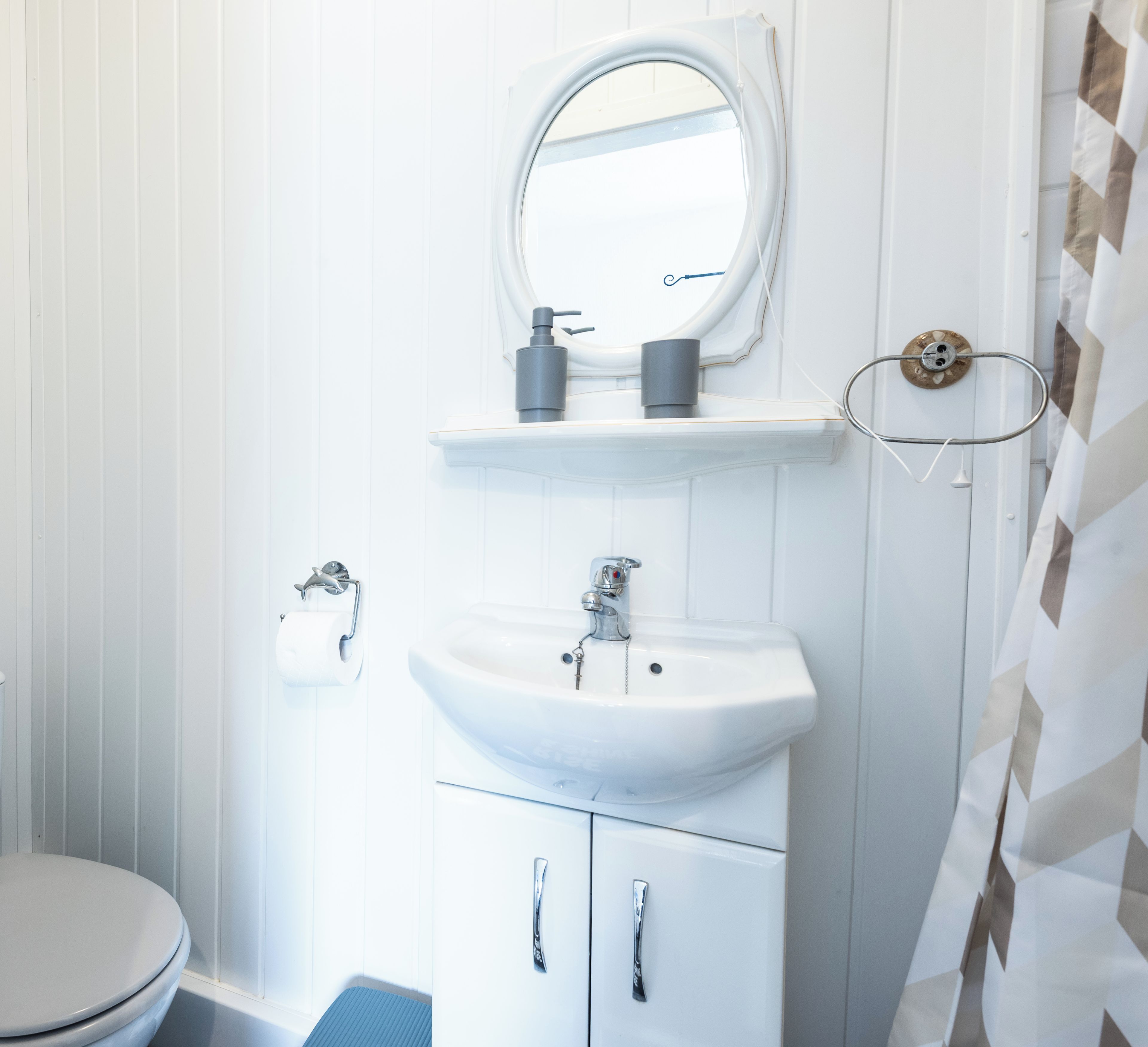 Une salle de bain avec un lavabo blanc, un miroir et des toilettes.
