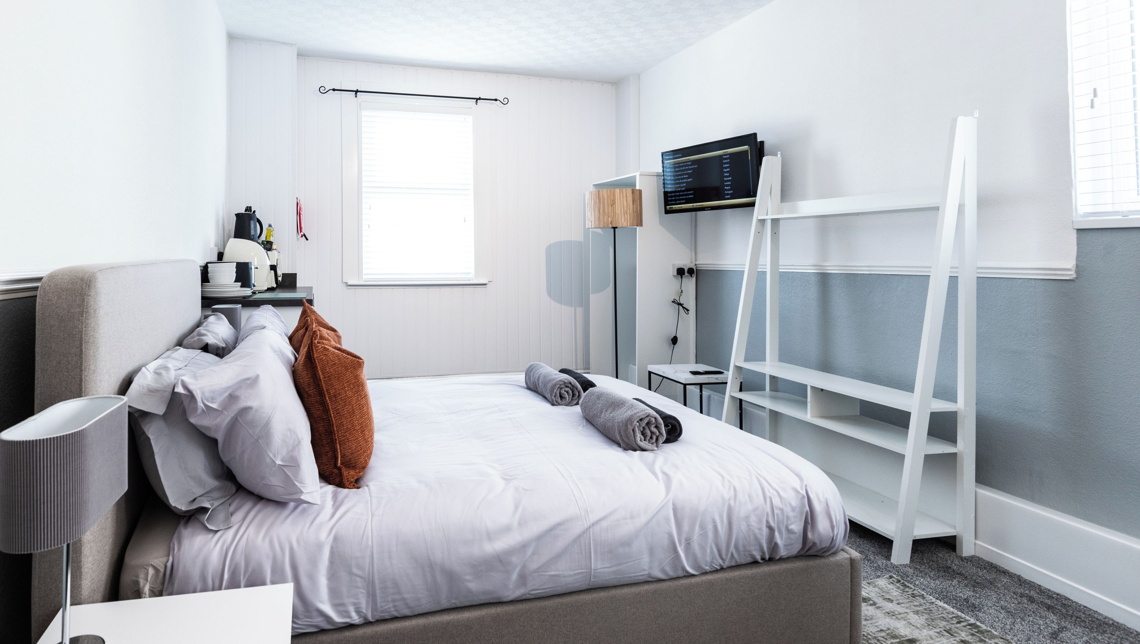 Una habitación de hotel con cama, escritorio, silla, televisor y ventana.
