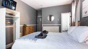 A bedroom with a bed, a TV, a wardrobe, and a mirror.