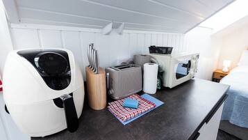 A compact kitchenette with a microwave, toaster, and a small table with a kettle and a basket.
