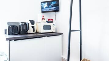 A kitchenette with a toaster, coffee maker, microwave, and a TV mounted on the wall.