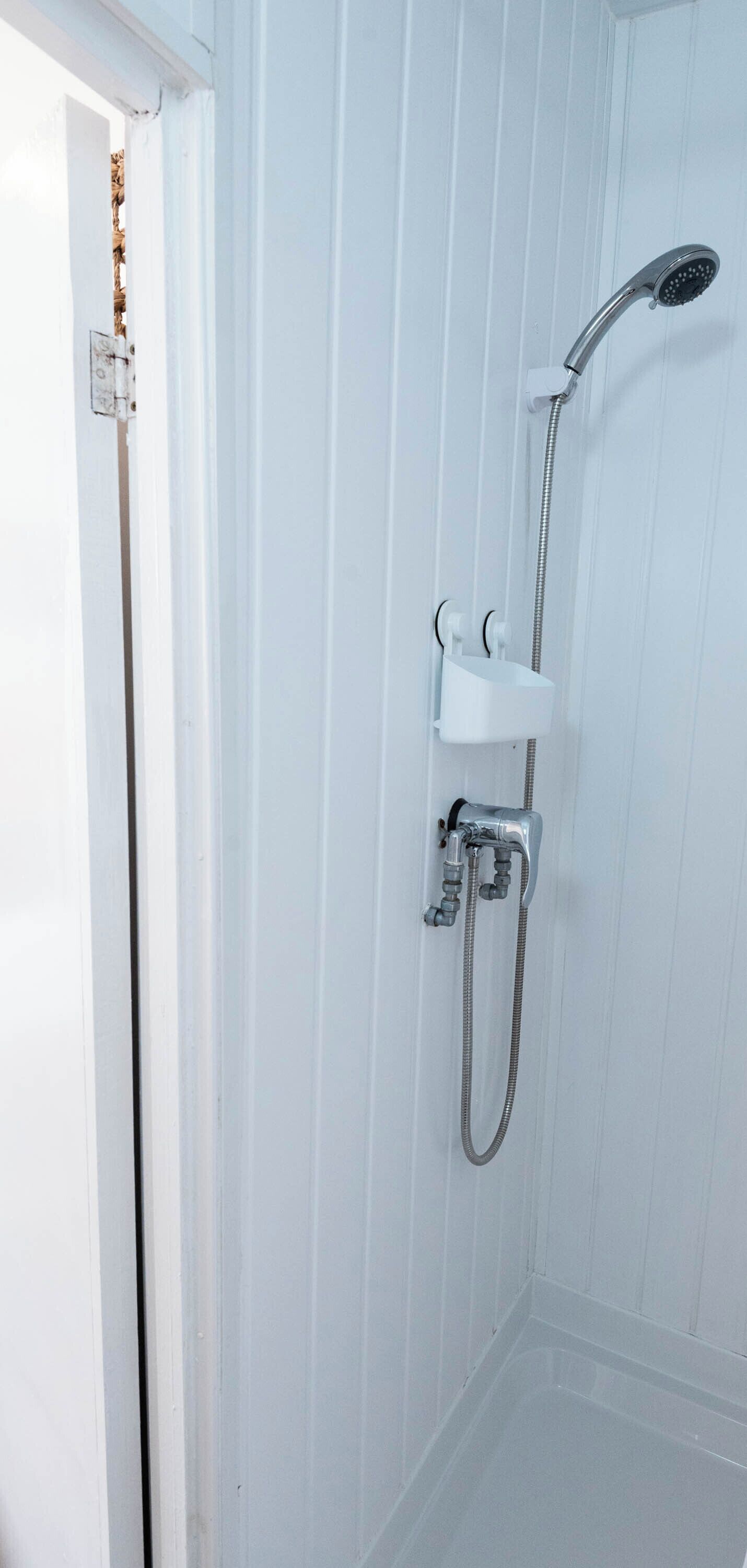 A shower area with a handheld showerhead, a handheld shower attachment, and a wall-mounted faucet.