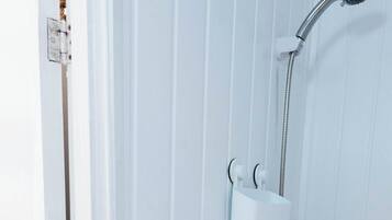 A shower area with a handheld showerhead, a handheld shower attachment, and a wall-mounted faucet.